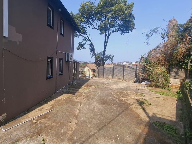 Rear exterior area featuring a concrete driveway, perimeter walling, and side elevation of the house with an installed air conditioning unit.