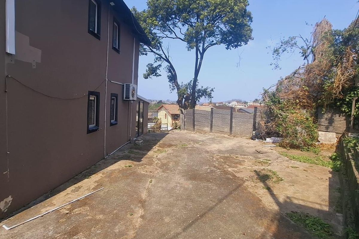 Rear exterior area featuring a concrete driveway, perimeter walling, and side elevation of the house with an installed air conditioning unit.