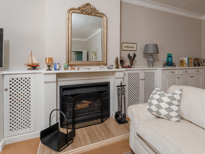 A well-maintained living room featuring a classic fireplace with integrated white cabinetry and decorative crown molding.