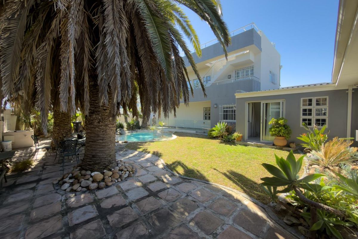 Rear garden area featuring a swimming pool, paved patio, and multi-story building facade with sliding door access.