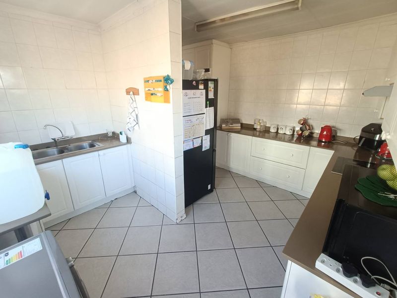 A functional kitchen featuring white cabinetry, laminate countertops, tiled splashbacks, and ceramic floor tiles, offering a practical layout for daily meal preparation.