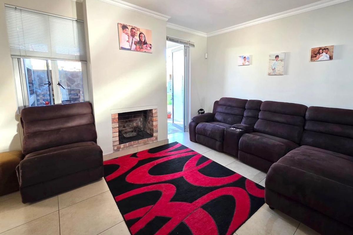 A comfortable living room featuring a built-in brick fireplace, tiled flooring, and direct access to an outdoor area through a glass door.