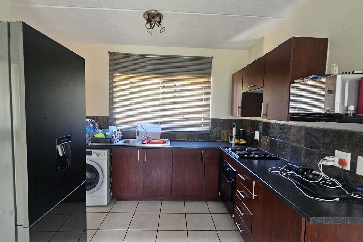 Functional kitchen featuring dark wood cabinetry, laminate countertops, tiled backsplash, and integrated oven and hob, offering a practical layout for daily use.