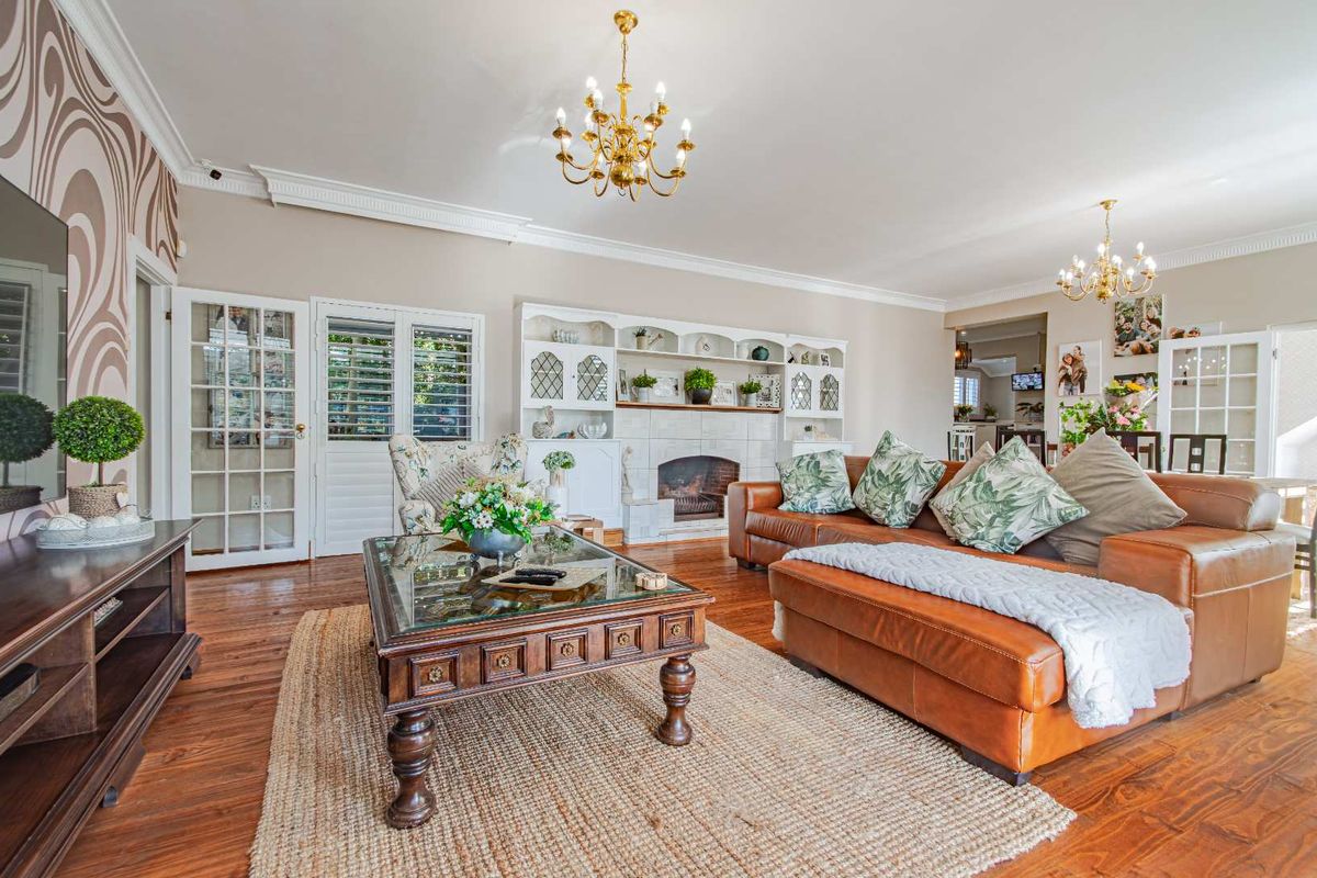 Spacious living room featuring hardwood flooring, a built-in fireplace with integrated shelving, crown molding, and classic chandelier lighting.