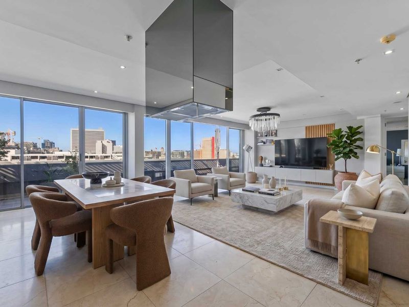 Spacious open-plan living and dining area featuring floor-to-ceiling windows with city views, modern tiled flooring, and a sleek suspended extractor hood.