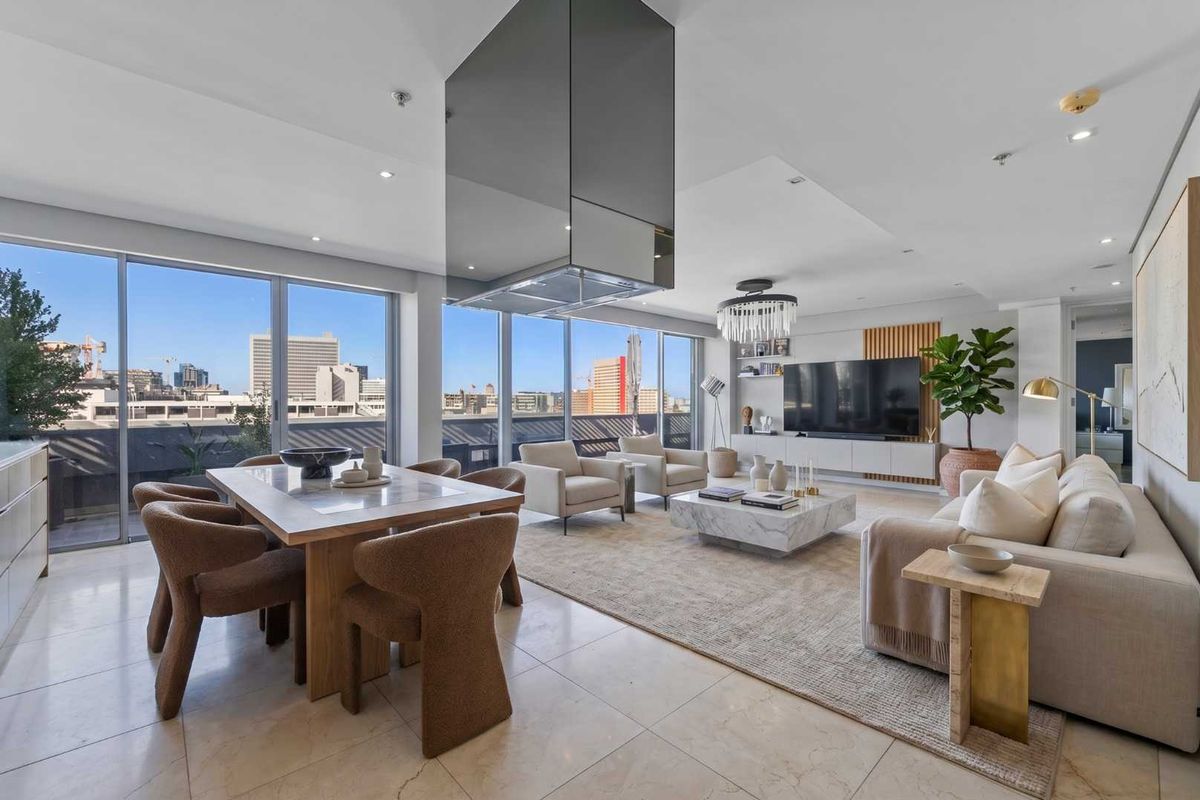 Spacious open-plan living and dining area featuring floor-to-ceiling windows with city views, modern tiled flooring, and a sleek suspended extractor hood.
