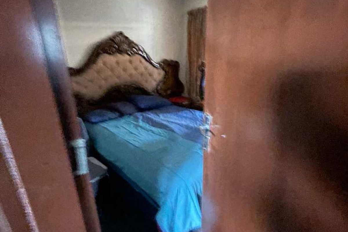 A view into a bedroom through a partially open wooden door, showing basic interior finishes and a compact layout.