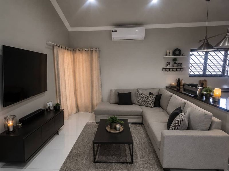 Modern open-plan living area featuring tiled floors, recessed lighting, a split-system air conditioner, and a breakfast bar overlooking the kitchen space.