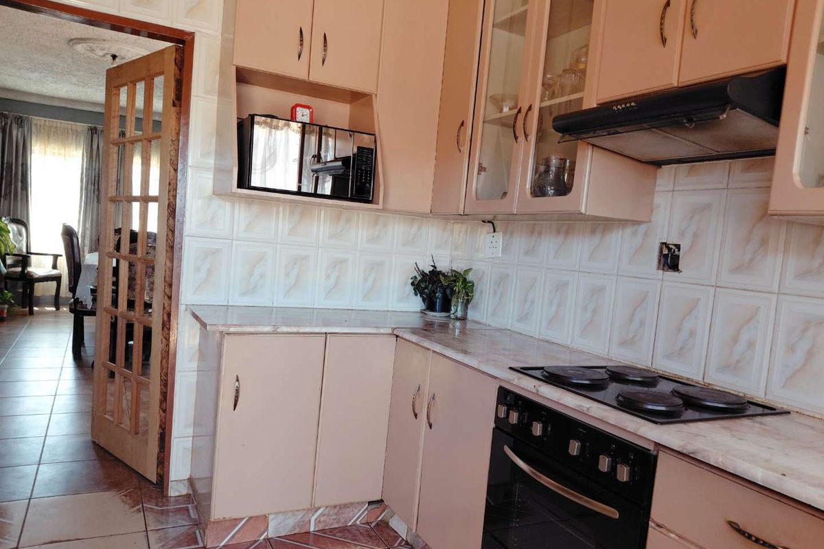 A functional kitchen featuring built-in cabinetry, laminate countertops, a built-in oven with hob, and tiled finishes throughout.