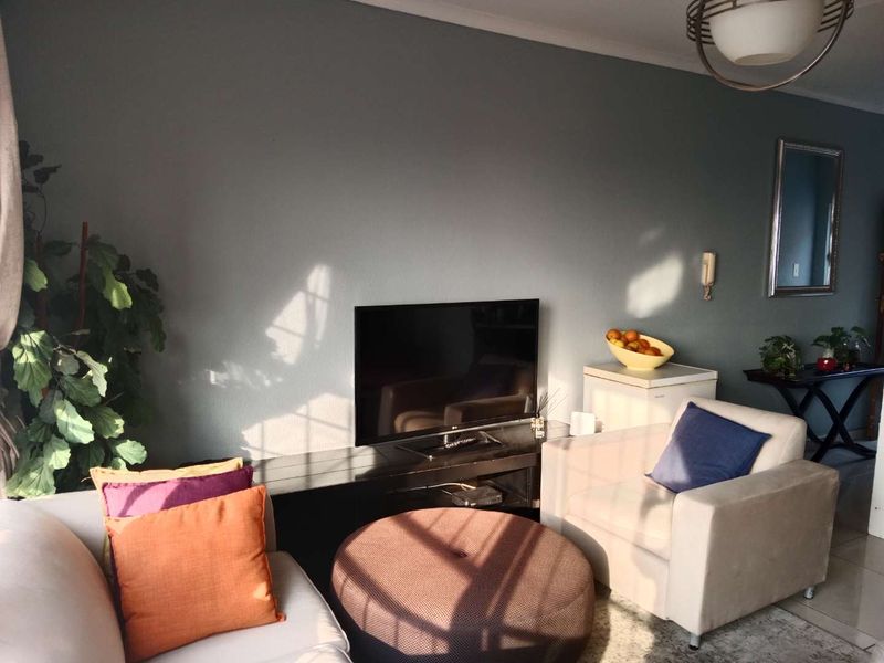 A comfortable living room featuring tiled flooring, a wall-mounted intercom system, and a central ceiling light fixture.