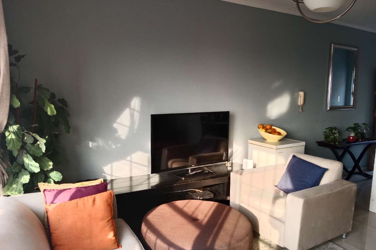 A comfortable living room featuring tiled flooring, a wall-mounted intercom system, and a central ceiling light fixture.