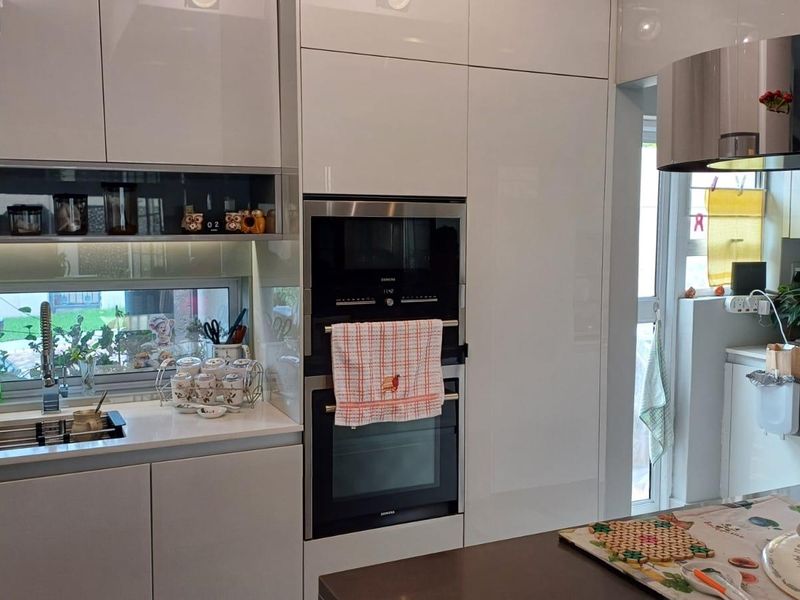 Modern kitchen featuring high-gloss white cabinetry, integrated appliances including an oven and microwave, quartz countertops, and a sleek undermount sink.