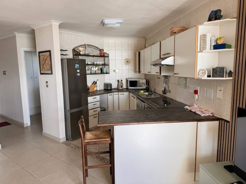 A functional kitchen featuring built-in cabinetry, laminate countertops, a breakfast bar, and tiled finishes, offering a practical layout for daily use.