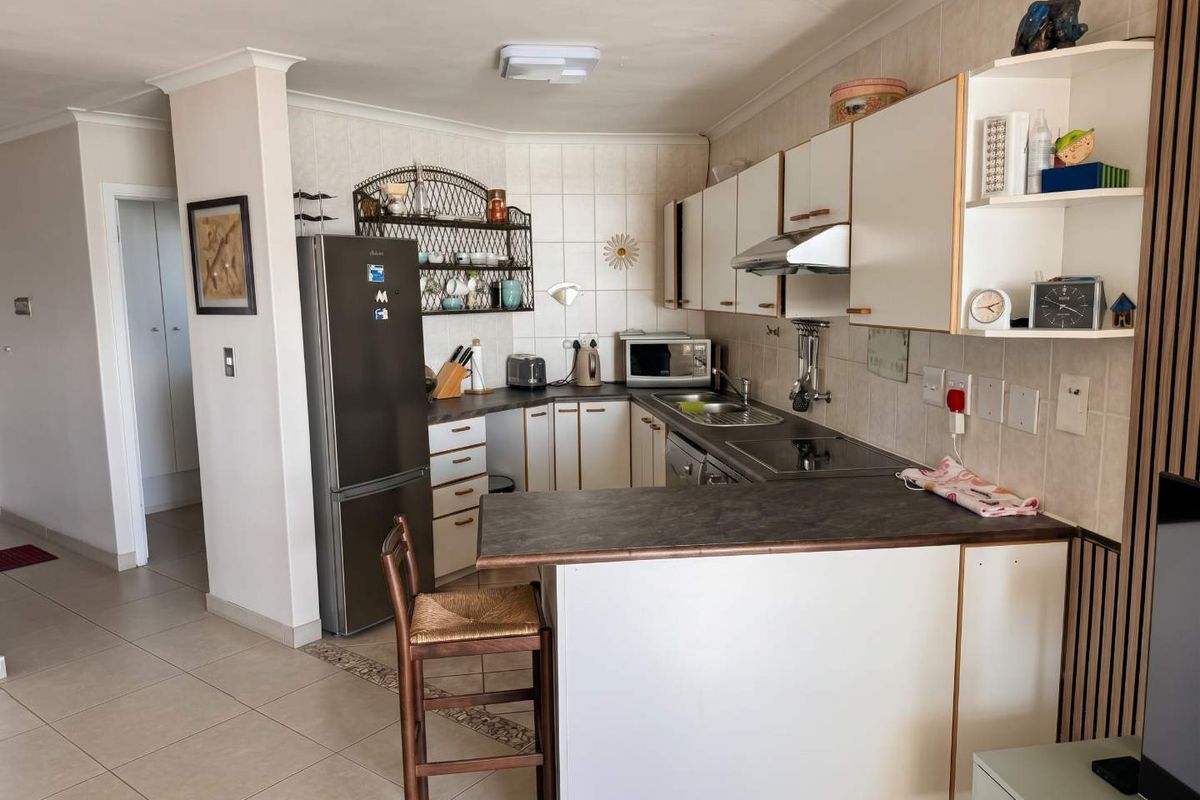 A functional kitchen featuring built-in cabinetry, laminate countertops, a breakfast bar, and tiled finishes, offering a practical layout for daily use.