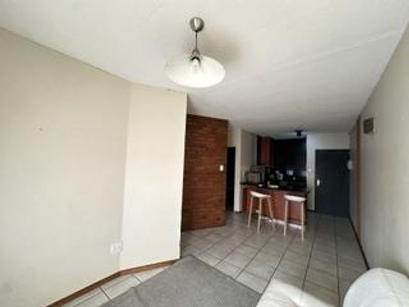 Open plan living area featuring tiled flooring and a compact kitchen with built-in cabinetry and counter space.