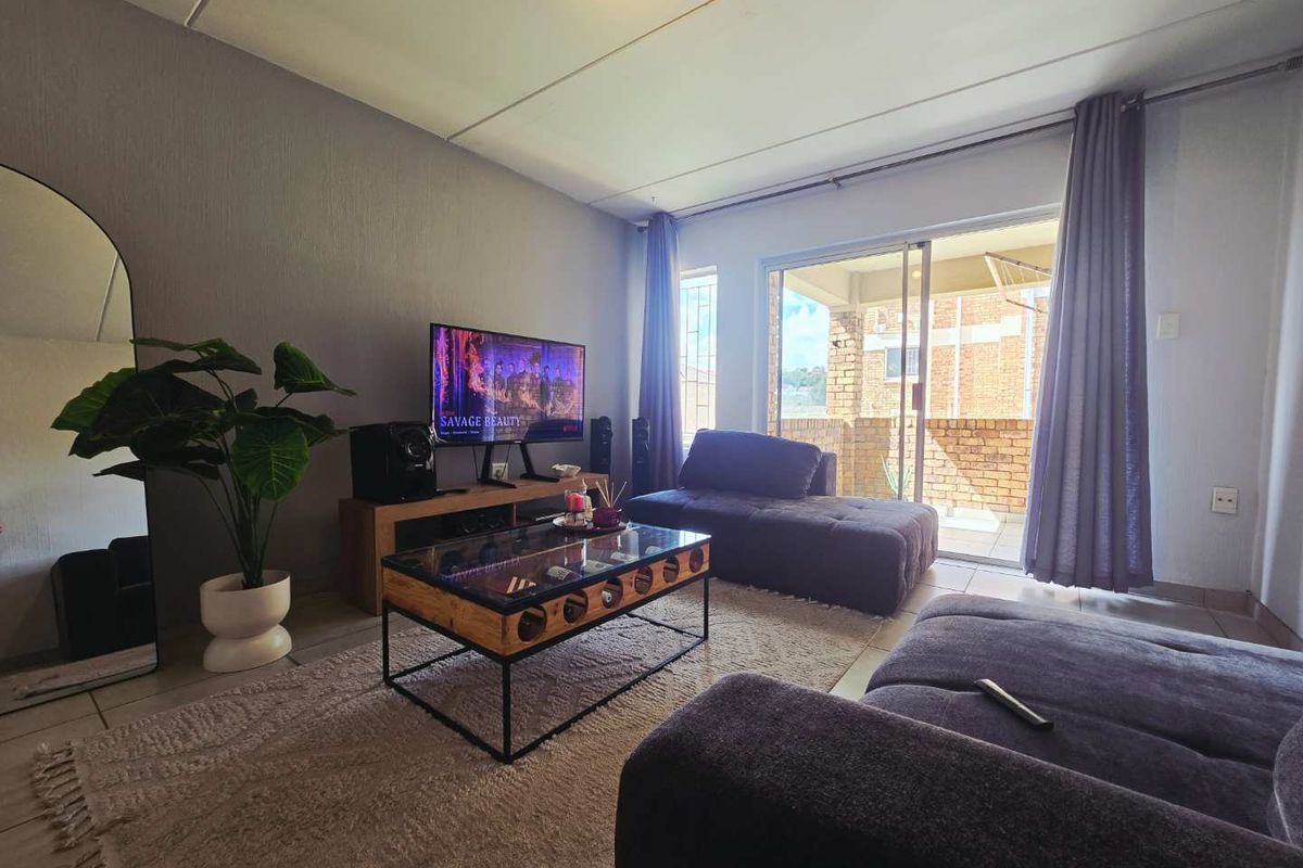 A comfortable living room featuring tiled flooring and a large sliding glass door that provides access to an outdoor balcony area.