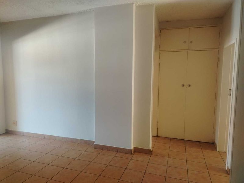 An empty bedroom featuring tiled flooring and a built-in cupboard with overhead storage.