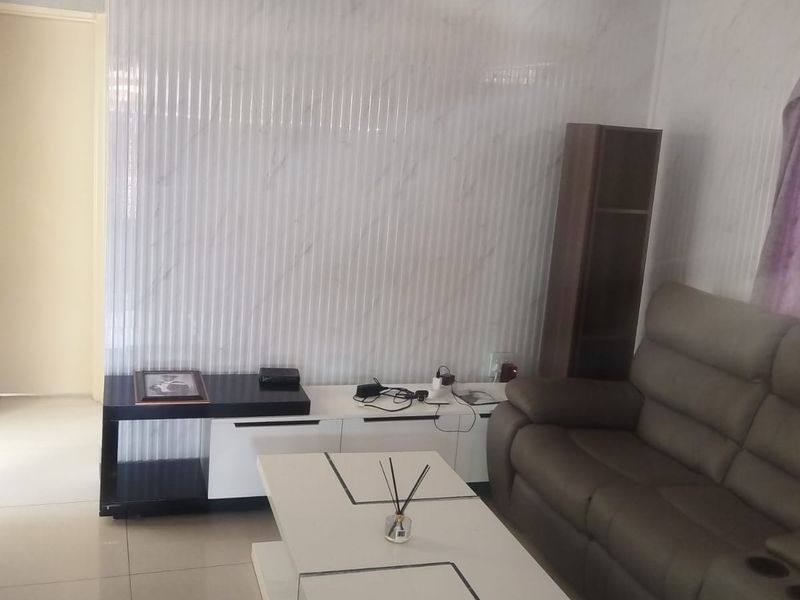 Living room featuring marble-effect wall cladding, tiled flooring, and decorative coving.