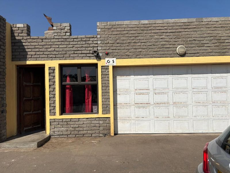 Front exterior view of the property featuring a garage door, brick facade, and main entrance door.