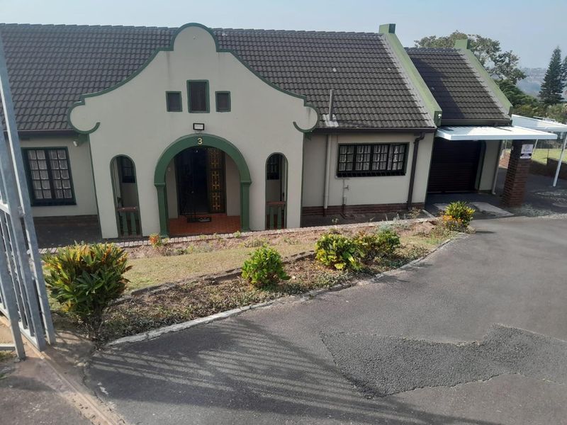 Front elevation of a house featuring a distinctive gabled entrance, tiled roof, attached garage, and an asphalt driveway.