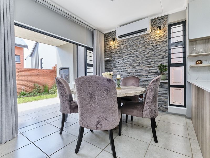 Modern open-plan dining area featuring a stone-clad accent wall, split-system air conditioning, and seamless flow to an outdoor patio through large sliding glass doors.