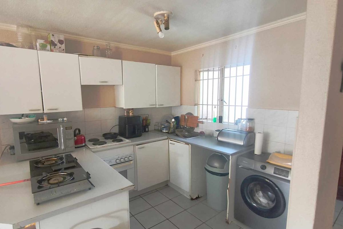 A functional kitchen featuring white cabinetry, tiled flooring, a built-in oven, and a tiled backsplash, offering potential for modernization and cosmetic updates.