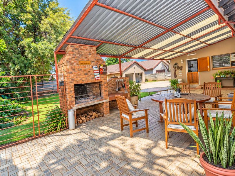 Covered outdoor patio featuring a built-in brick braai, paved flooring, and a corrugated metal roof, ideal for outdoor entertaining.
