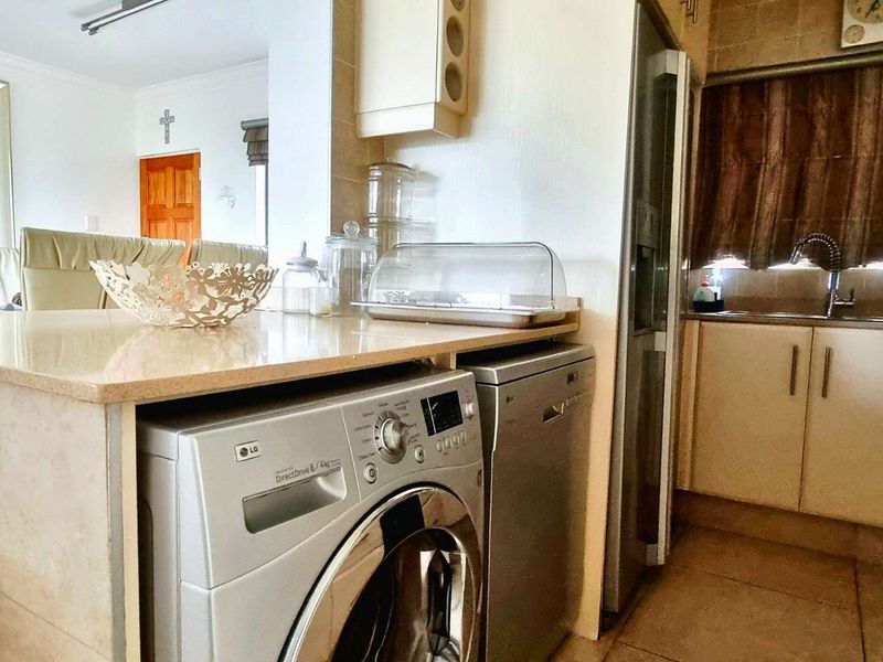 A functional kitchen area featuring built-in cabinetry, stone countertops, a stainless steel sink, and tiled finishes, seamlessly integrated with the adjacent living space.