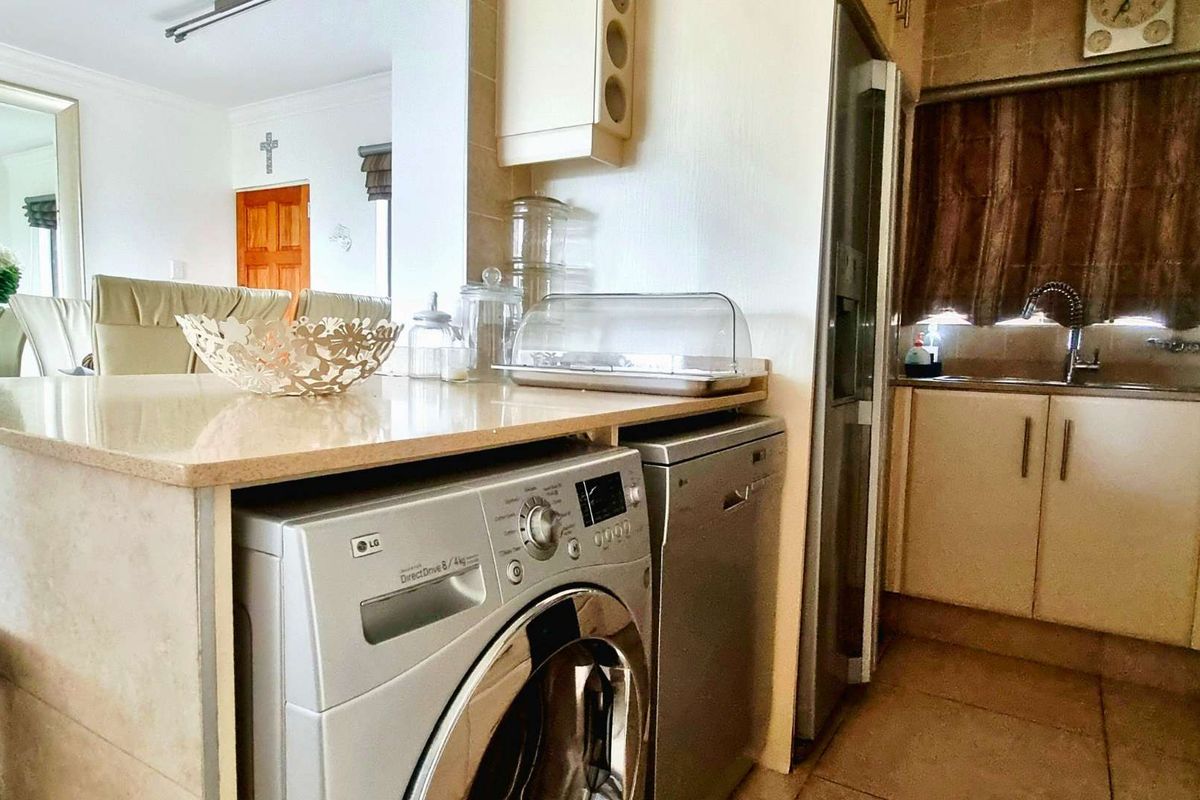 A functional kitchen area featuring built-in cabinetry, stone countertops, a stainless steel sink, and tiled finishes, seamlessly integrated with the adjacent living space.