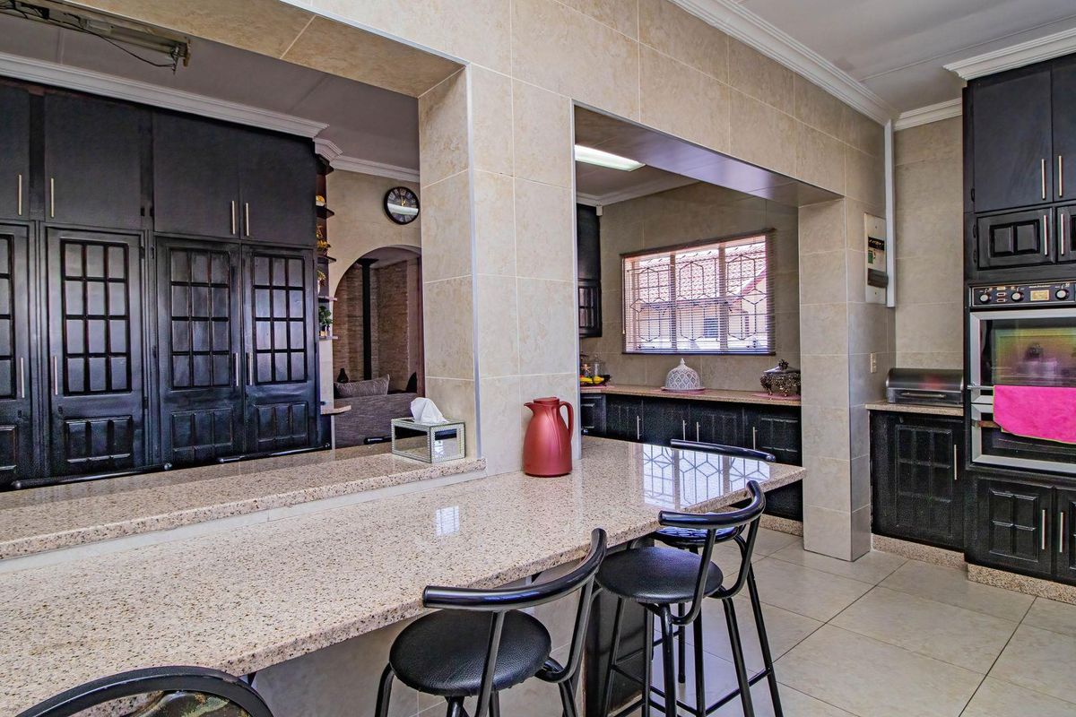 A spacious kitchen featuring dark cabinetry, granite countertops, a breakfast bar, and a built-in double oven, offering a functional and well-defined cooking space.
