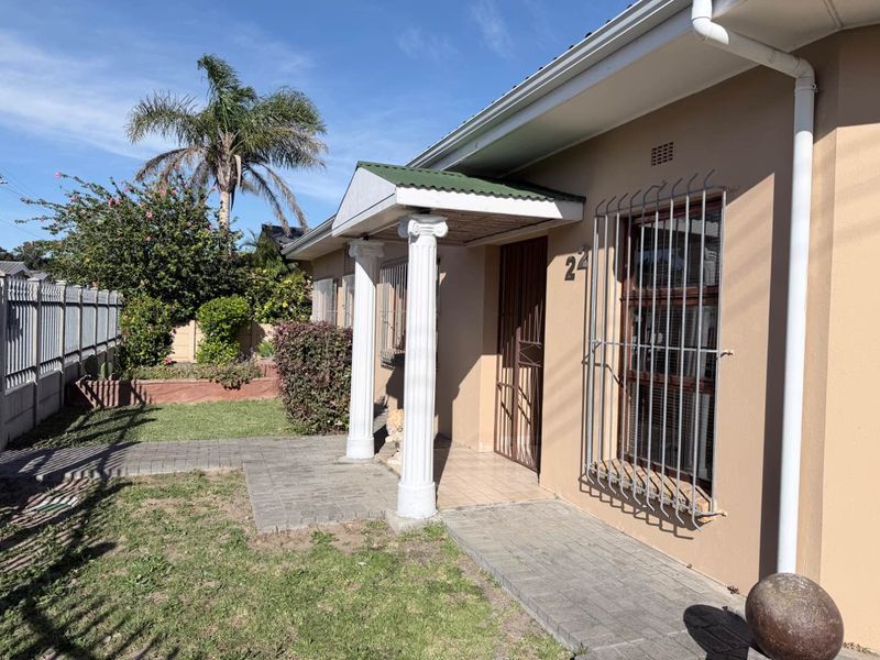 Front exterior view of the house featuring a covered entrance porch with decorative columns, security bars on windows, and a paved walkway.