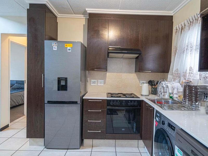 A functional kitchen featuring dark wood cabinetry, stone countertops, a built-in oven with hob, and tiled flooring, providing a practical workspace.