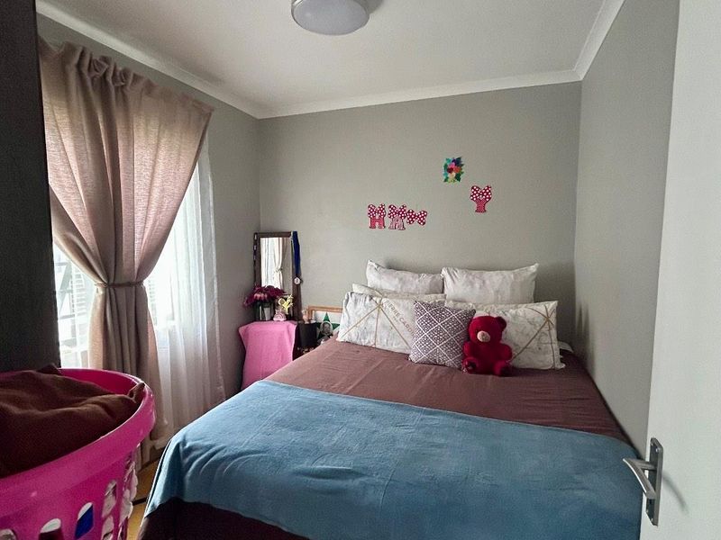 A compact bedroom featuring neutral wall paint, a ceiling light fixture, and a window with installed curtain rods.