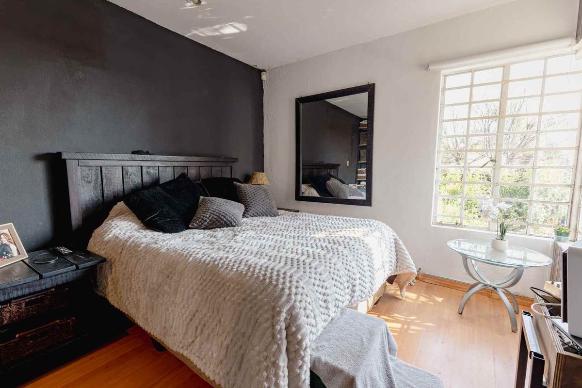 A bedroom featuring laminate flooring and a large grid-pattern window, providing natural light and a view of the exterior.