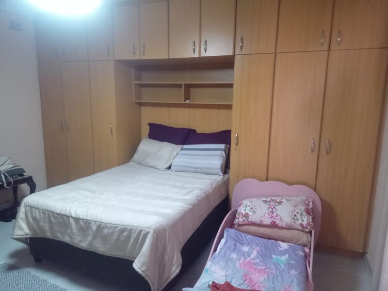 Bedroom featuring extensive floor-to-ceiling built-in wooden cabinetry with integrated overhead storage and shelving units.