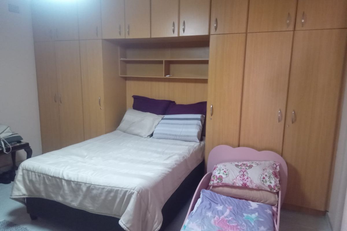 Bedroom featuring extensive floor-to-ceiling built-in wooden cabinetry with integrated overhead storage and shelving units.