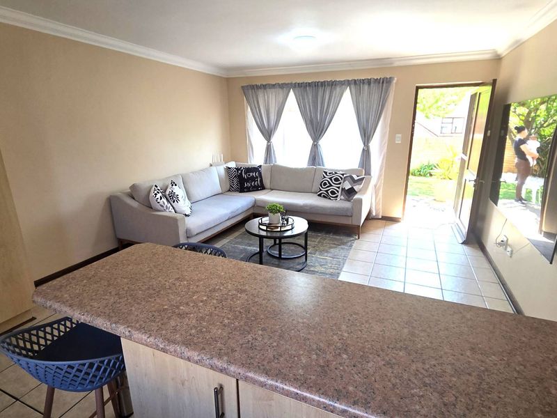 Open plan living area featuring tiled flooring, a breakfast bar, and direct access to the outdoor space through a sliding door.