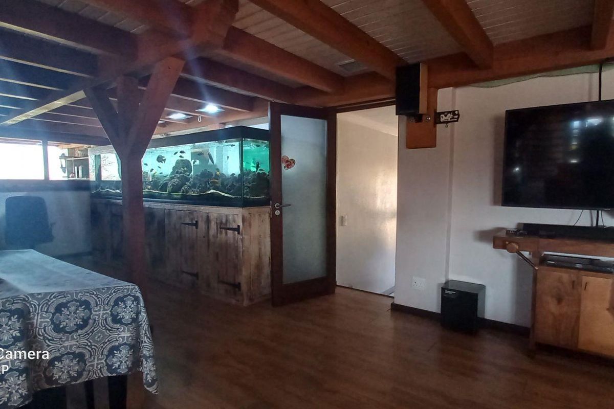 Spacious living area featuring exposed timber ceiling beams, wooden flooring, and a built-in aquarium partition.