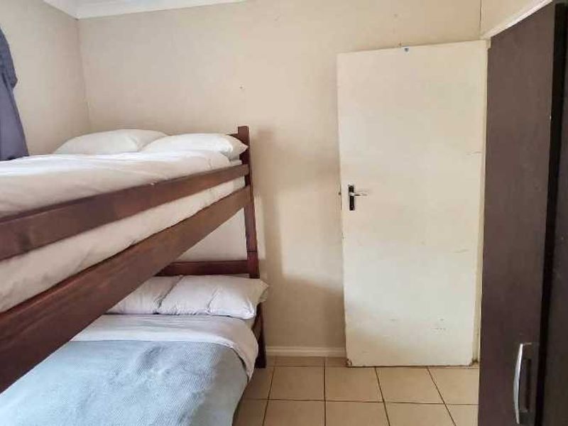 A functional bedroom featuring tiled flooring and neutral wall finishes, providing a practical space for sleeping arrangements.