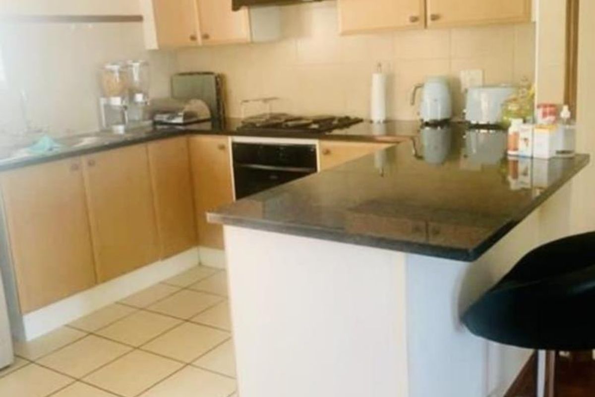 Functional kitchen featuring light wood cabinetry, granite countertops, built-in oven, gas hob, and a breakfast nook area with tiled flooring.