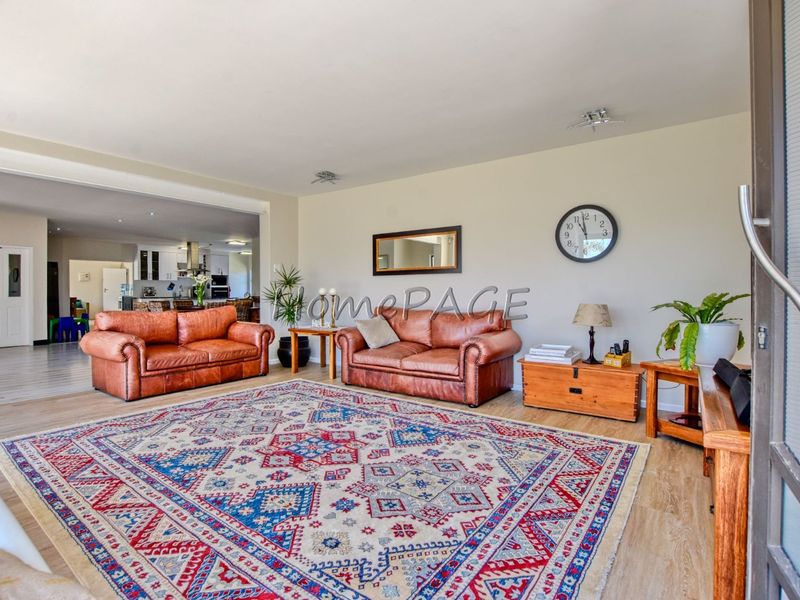 Spacious open-plan living area featuring light-toned laminate flooring and seamless flow into the adjacent kitchen space.