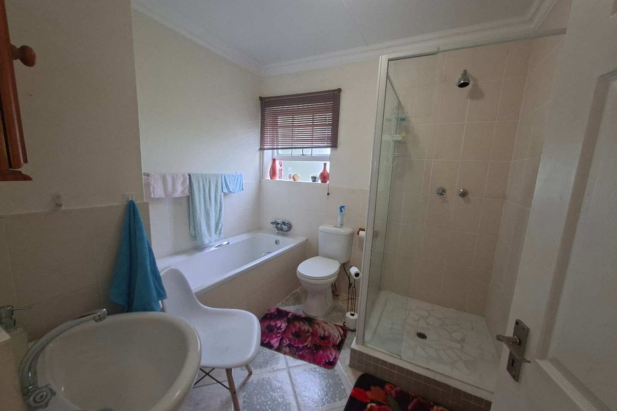 A functional bathroom featuring a separate shower enclosure, built-in bathtub, pedestal basin, and toilet with tiled finishes throughout.