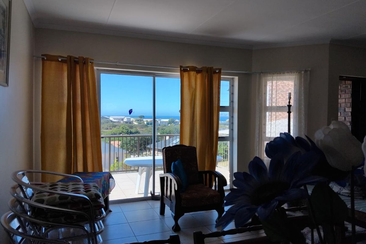 A bright living area featuring large sliding glass doors that open onto a balcony with scenic coastal views.