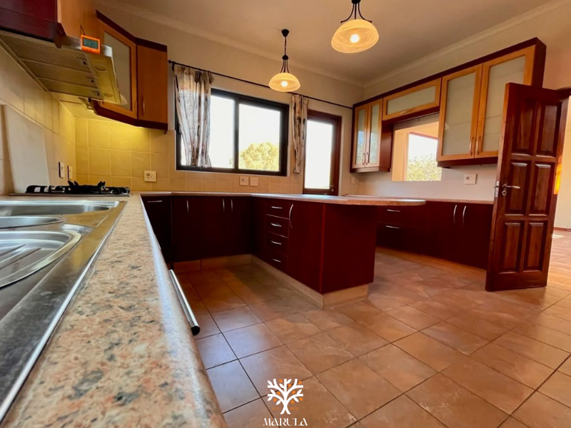Spacious kitchen featuring dark wood cabinetry, laminate countertops, a gas hob with extractor, and tiled flooring, offering a functional layout for meal preparation.