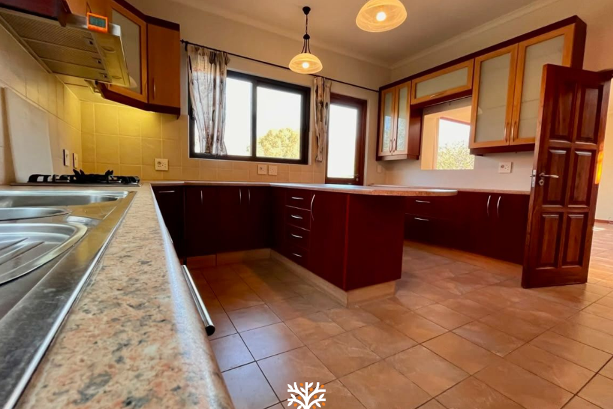 Spacious kitchen featuring dark wood cabinetry, laminate countertops, a gas hob with extractor, and tiled flooring, offering a functional layout for meal preparation.