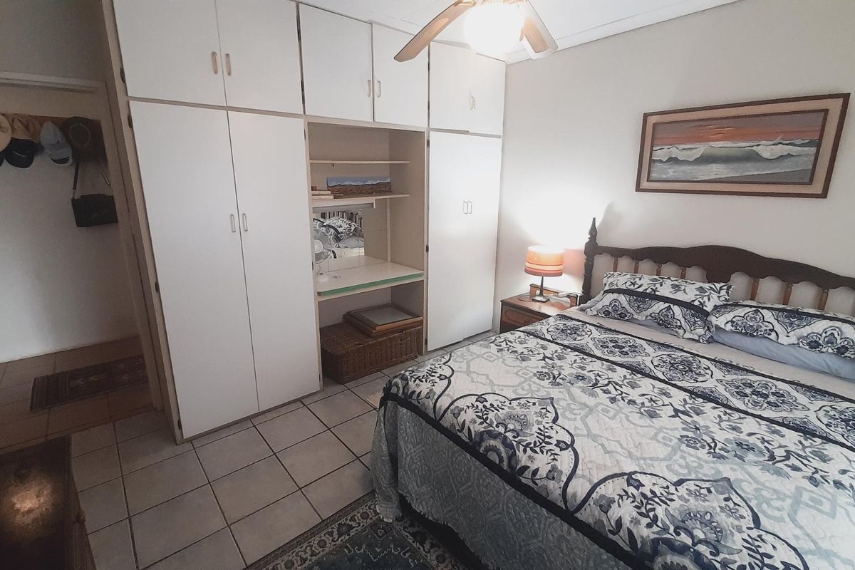 A bedroom featuring built-in cupboards with integrated shelving, a ceiling fan, and tiled flooring.