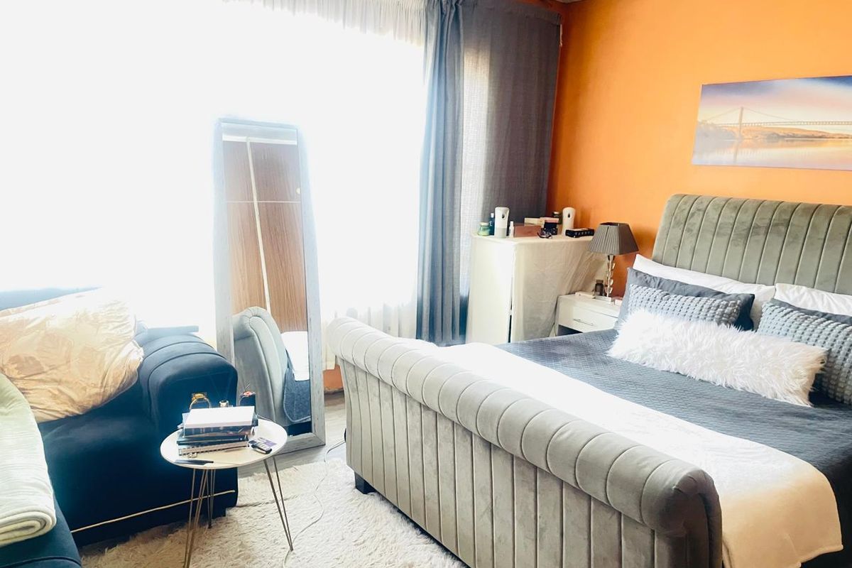 A bedroom featuring a large window with curtains, providing natural light to the space.