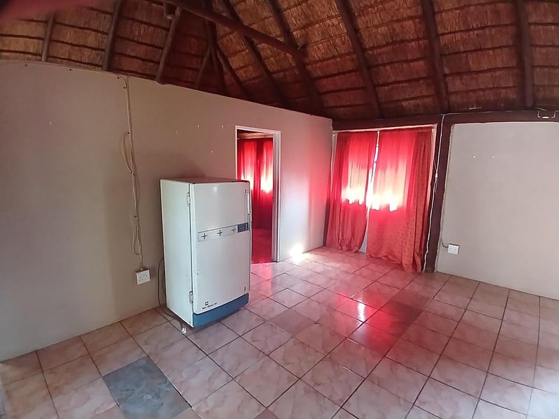 Living area featuring a traditional thatched roof with exposed timber rafters and ceramic tiled flooring, offering a rustic cottage aesthetic.