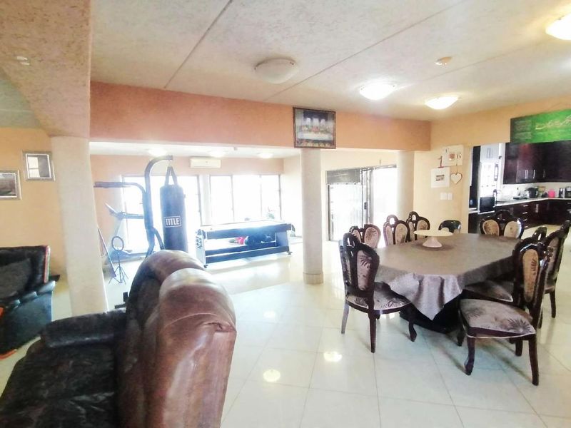 Spacious open-plan living and dining area featuring tiled flooring, structural columns, and direct access to the outdoors through sliding glass doors.