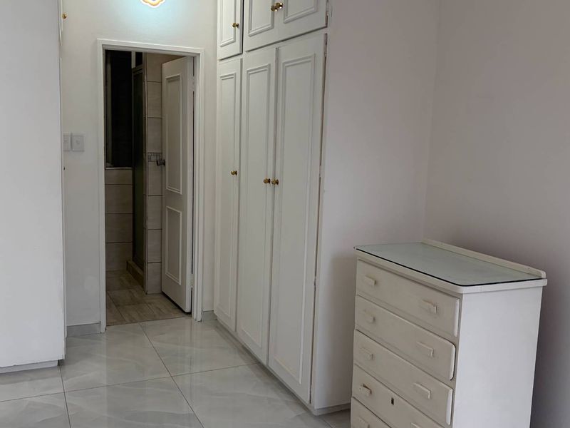 A bedroom featuring built-in cupboards, tiled flooring, and direct access to an adjoining bathroom.